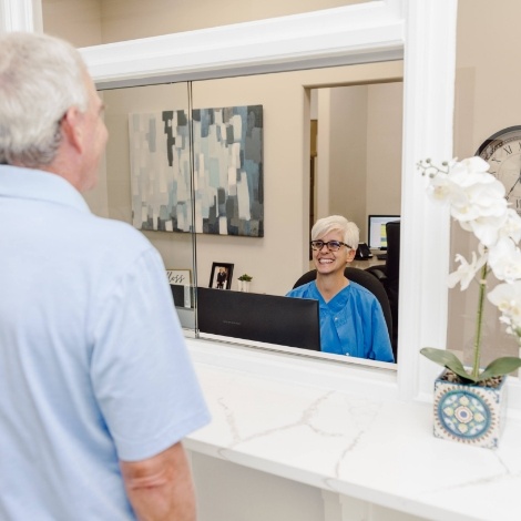 Dental team member at front desk smiling at a patient