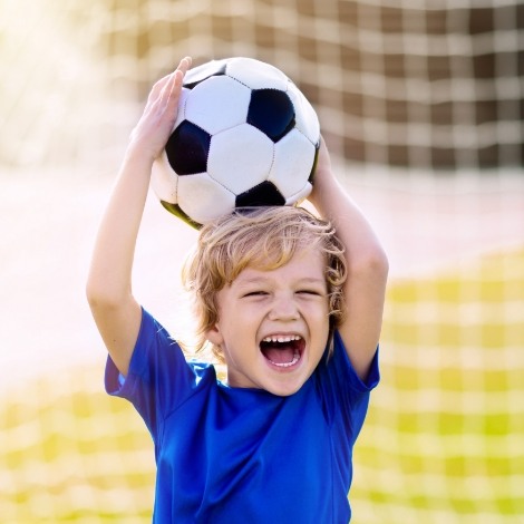 Laughing boy holding soccer ball above his head