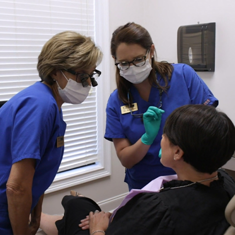 Two dentists explaining T M J treatment to a dental patient
