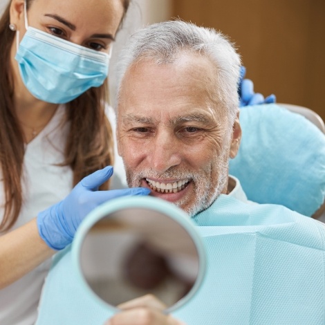 Senior dental patient seeing his new smile in mirror