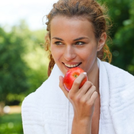 Young woman outdoors eating a red apple