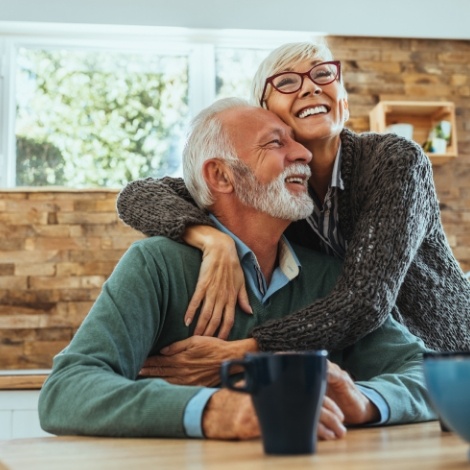 Senior man and woman hugging at coffee table