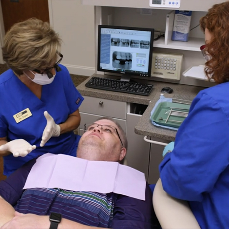 Two dentists talking with patient in dental chair
