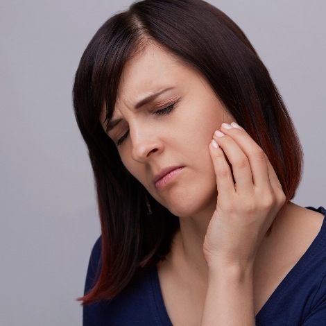 Woman holding the side of her jaw in pain