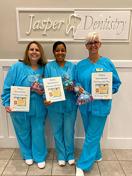 Three dental team members holding pamphlets and goodie bags