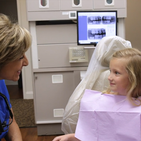 Fort Mill dentist smiling at young girl in dental chair