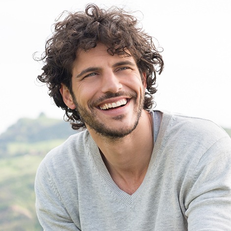 Man in grey shirt laughing and smiling