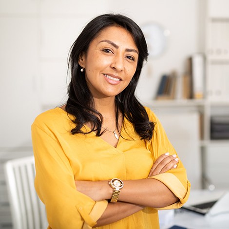 Woman in yellow shirt smiling with arms crossed