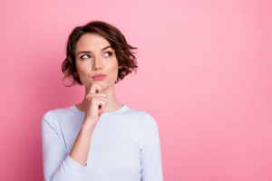 Woman striking a questioning post on pink background